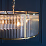 close up image of ribbed glass pendant light with antique brass metalwork edges and bulb within emitting warm glow