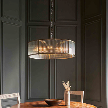 slightly angled image of ribbed glass pendant light emitting warm light from 8 bulbs within