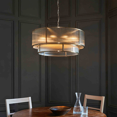 image of large tiered ribbed glass pendant light emitting warm light over dining table