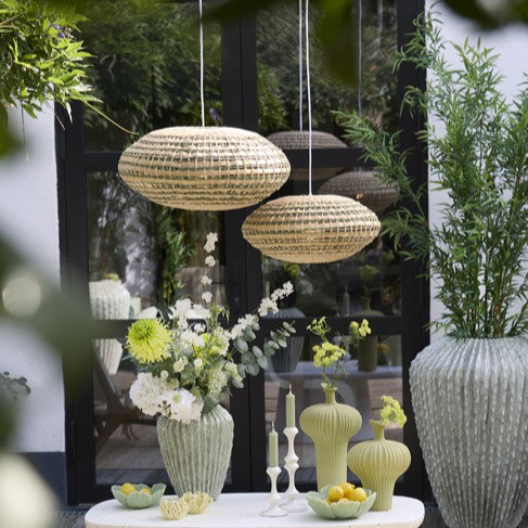 image of two oval woven rattan hanging light shades in a conservatory, over a small table