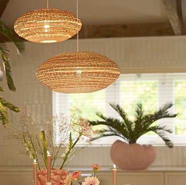 image cut out on white background of larger woven oval hanging lamp shade in natural and terracotta colours