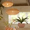 image of two woven oval hanging light shades in a dining room, in natural and terracotta colours