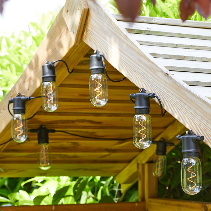 image of eight vintage filament lights strung at the top of a wooden pergola during the day