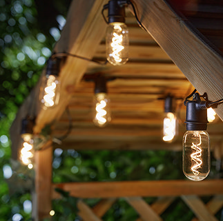 image of vintage rectangular filament lights glowing warm white, hung at the top of a pergola at dusk