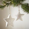 small rustic star and its larger counterpart hanging next to each other on a christmas tree, with cream wall in the background.