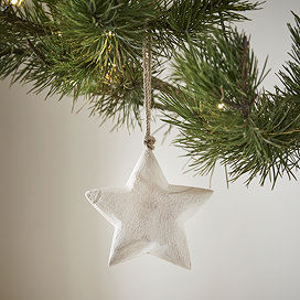 close up on small white wood rustic star, hanging from a christmas tree.