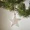 close up on small white wood rustic star, hanging from a christmas tree.