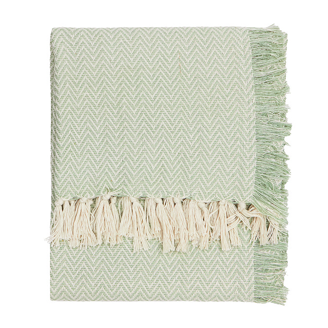 image cut out on white background of leaf green patterned throw with natural tasseled edges folded up