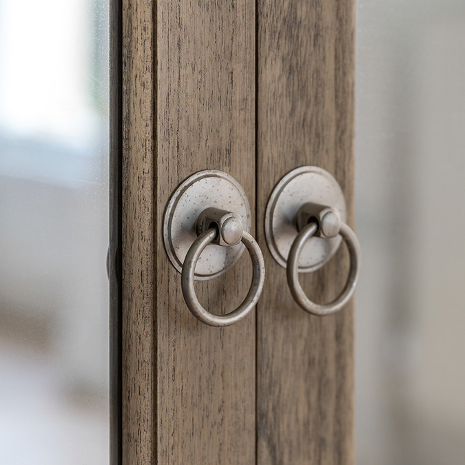 close up image of small round handles of wardrobe, sleek wood and mirrored doors
