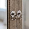 close up image of small round handles of wardrobe, sleek wood and mirrored doors