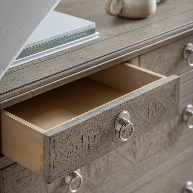 close up on top of ashy wooden chest of drawers, with smallest top drawer pulled out