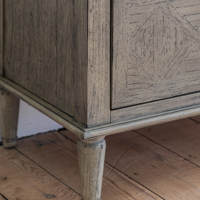 close up image of legs and lower half of ashy wood patterned chest of drawers
