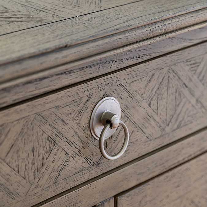 close up image of small hoop ring handles of ashy wood 7 drawer chest