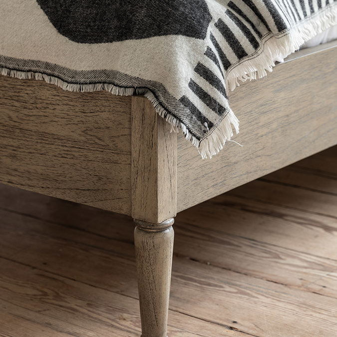 close up image on bottom half of solid wood bed with subtle pattern