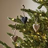 small wooden heart decorations hanging on branches of a lit christmas tree