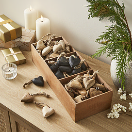 image of wooden box divided into three small sections, each containing wooden heart decorations in three colours - cream, black, and wood - with brown string