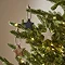 star hanging decorations on branches of a lit christmas tree