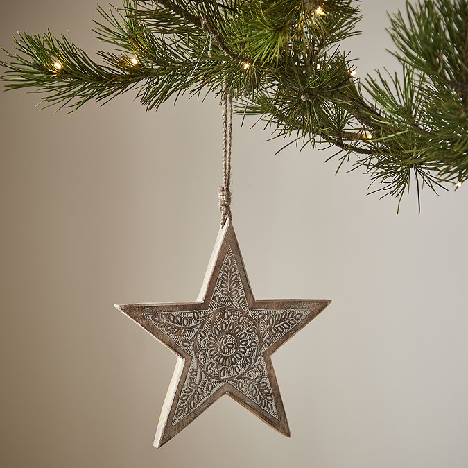 wooden patterned star hanging from a christmas tree