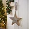 wooden patterned star hanging on a door handle with christmas tree in the background
