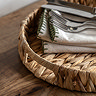close up on left woven round tray with linen napkins inside