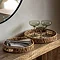pair of woven round trays, one slightly smaller than the other, displayed on a side table storing cutlery, napkins and glasses.