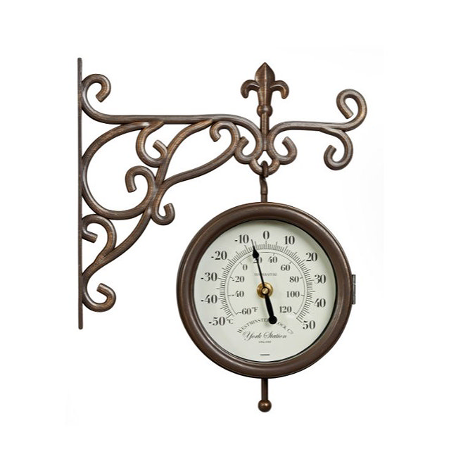 image cut out on white background of brown station clock with intricate ivy-style arm and round face with arabic numbers