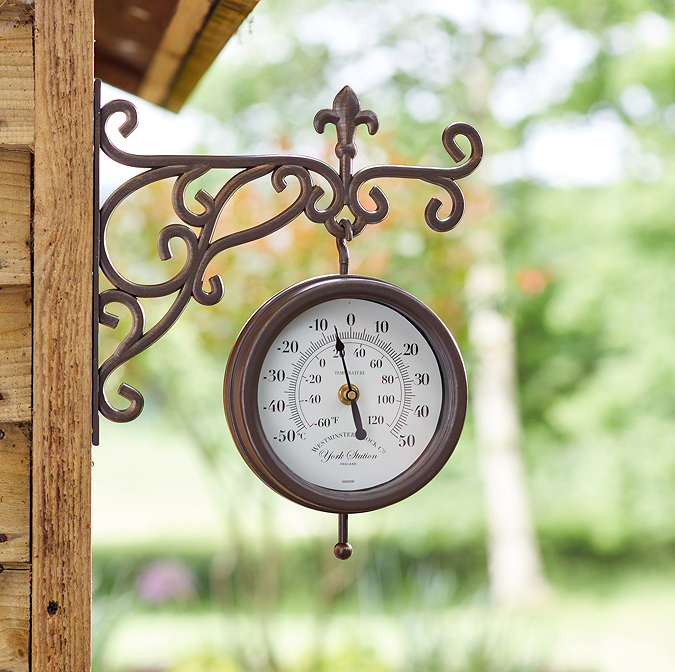 image of station wall clock in brown, with intricate arm and small arabic numbers