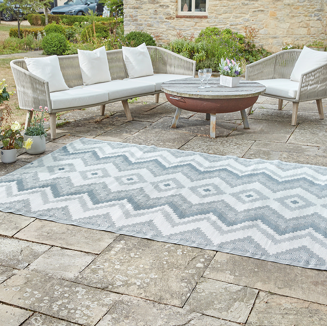 image of slate grey-blue zigzag rug on grey patio next to chic rattan lounge set